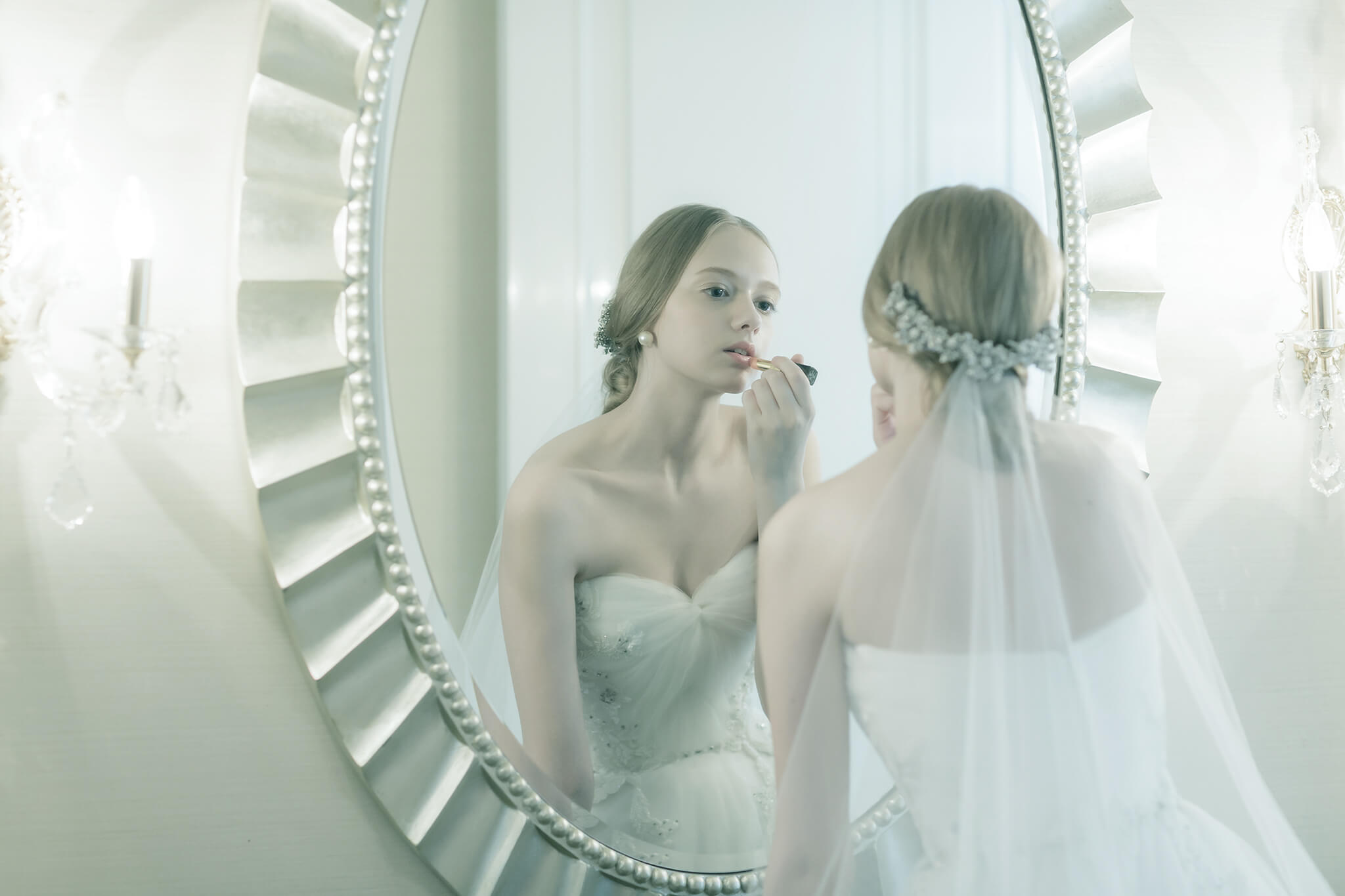 大きな鏡の前で化粧直しをする新婦のイメージ写真