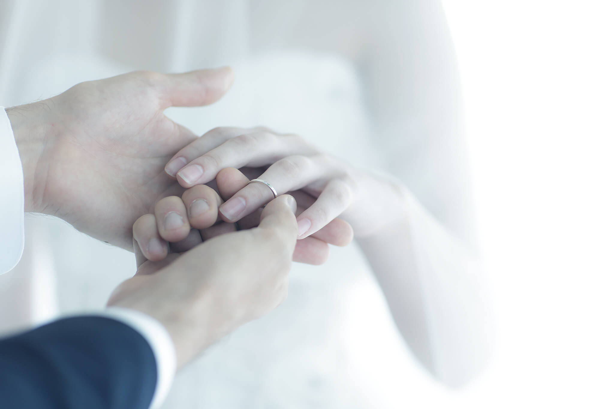 新婦の手に結婚指輪をはめようとしている新郎の写真