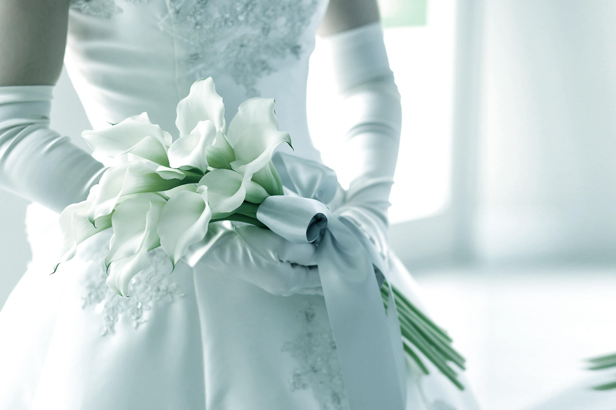 ウェディングドレスに身を包み花を手に持つ新婦のイメージ写真