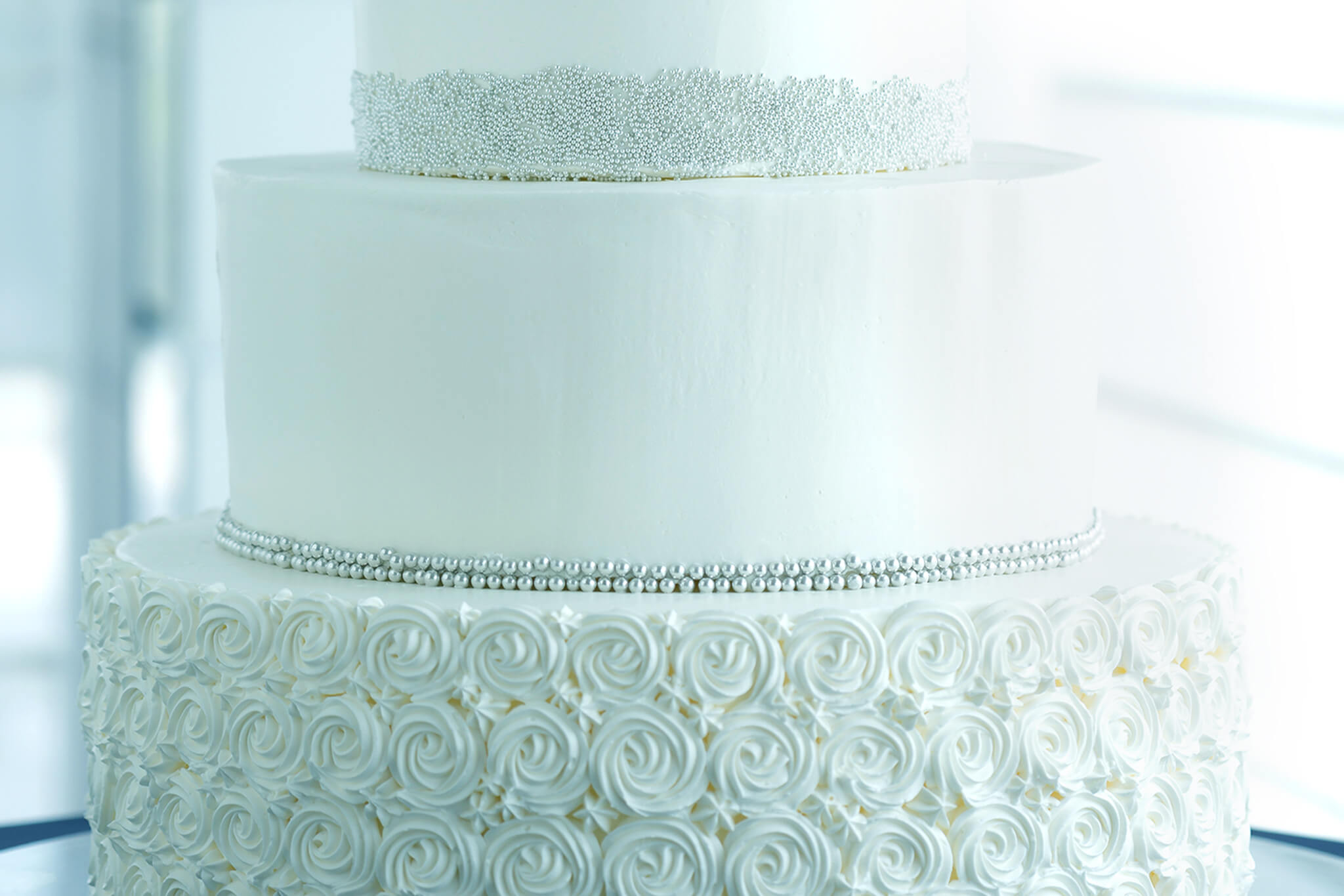 繊細なデコレーションが施された純白のウェディングケーキの写真